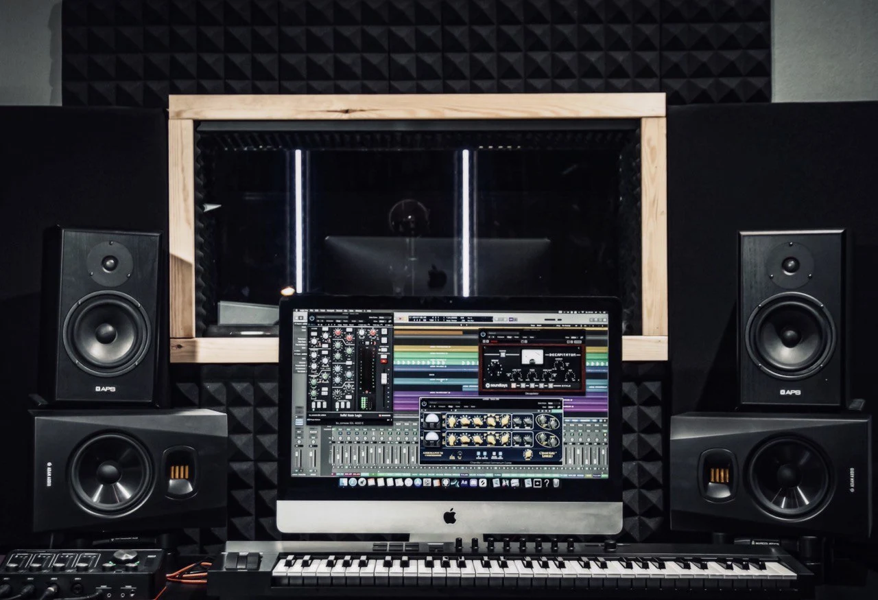 Studio desk with monitors, subs and a keyboard controller