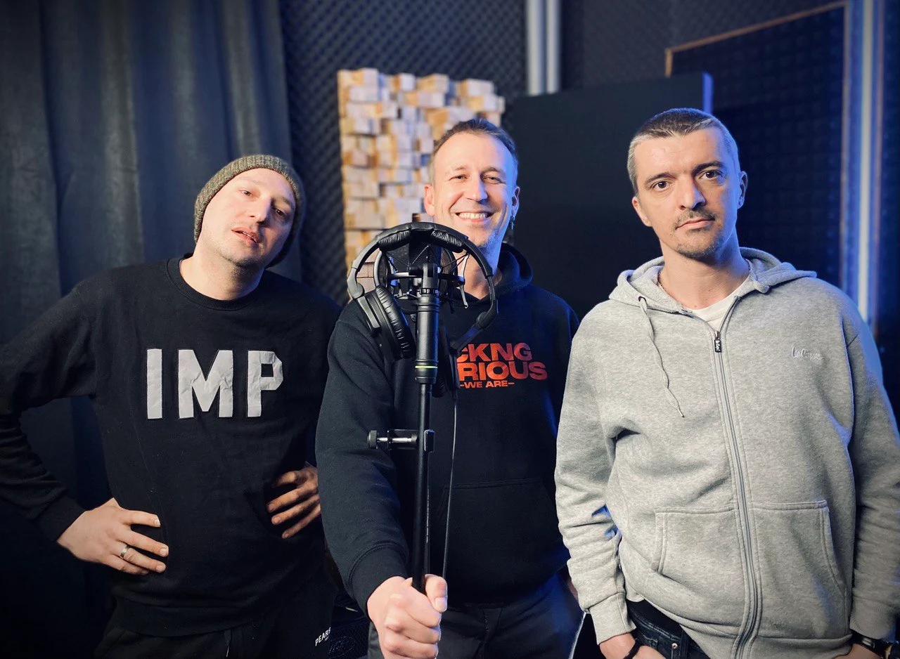 Three engineers standing around a microphone at the studio